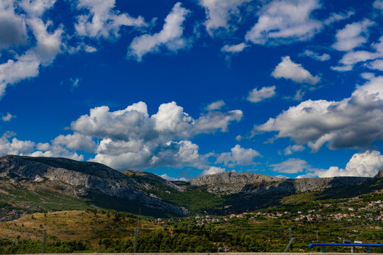 View of the rugged hills and Mediterranean landscape under a bright blue sky with fluffy white clouds in Hvar, Split-Dalmatia County, Croatia.