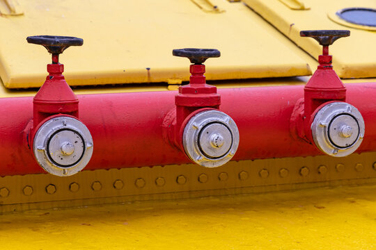 View of three red fire hydrants mounted on a yellow industrial surface in Leuvehaven, Rotterdam, South Holland, Netherlands.