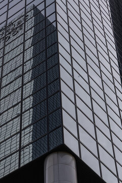 View of the corner of a modern glass skyscraper with reflective windows and a grid pattern in Rotterdam, South Holland, Netherlands.