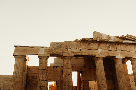 View of the ancient Parthenon temple at the Acropolis with weathered marble columns and stone architecture against a clear sky in Athens, Greece.
