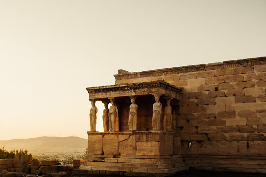 View of the Porch of the Caryatids at the Erechtheion on the Acropolis with ancient marble columns and statues under a warm sunset sky in Athens, Greece.