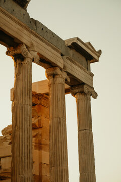 View of Acropolis with ancient marble columns illuminated by warm golden hour light, Athens, Greece.