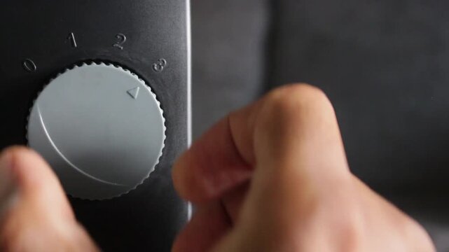 Hand turning mechanical knob dialing from 0 to 3 on device close up