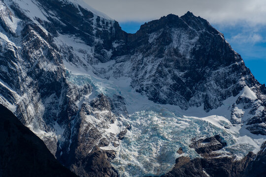 View of the snow-capped peaks and glacier of the Cordillera del Paine mountain range under a clear blue sky in Torres del Paine, Magallanes, Chile.