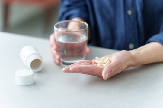 大量の薬を飲む女性の手元