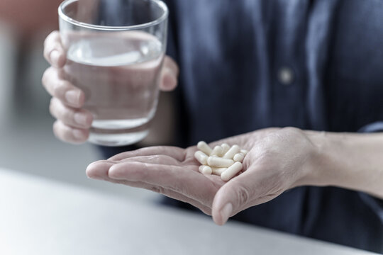 大量の薬を飲む女性の手元