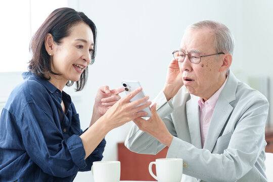 スマートフォンの説明を受ける難聴の高齢者人物,