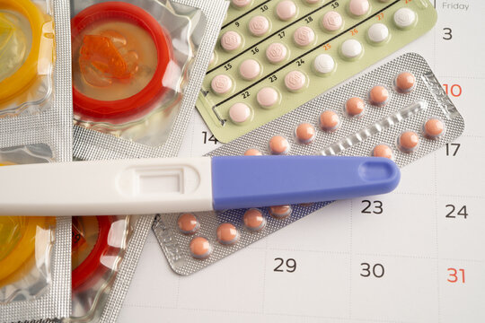 Pregnancy test and birth control pills on calendar, contraception health and medicine.