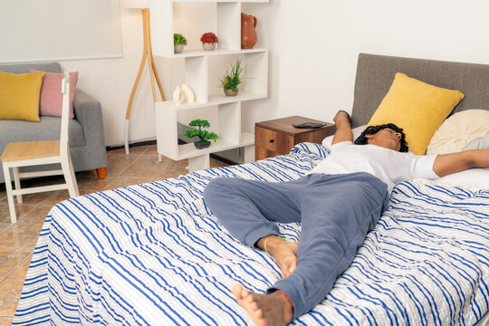 Young man waking up stretching in bed