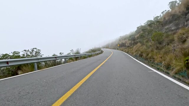 Winding Mountain Highway through Misty Highlands Seen from a Moving Car. Vehicle POV.