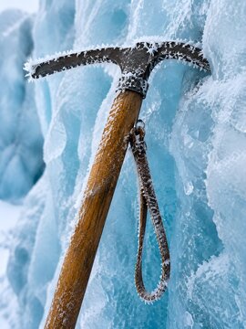 Vintage wooden shafted ice axe embedded in a serac wall with frost rimed head and leather loop