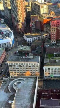 Aerial view looking down on Gastown streets in downtown Vancouver, with heritage brick buildings, rooftops and quiet intersections in warm evening light.