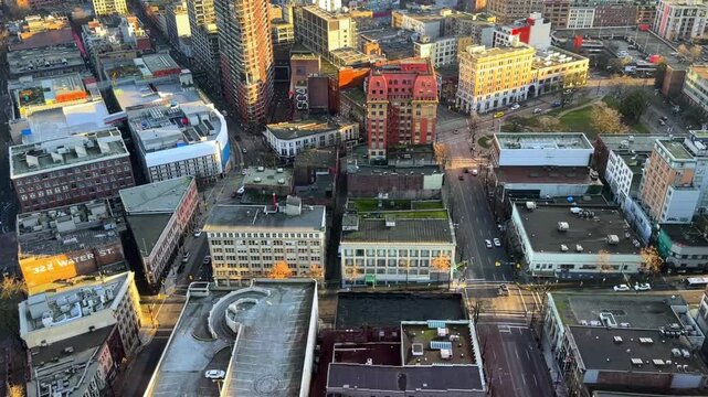 Aerial view looking down on Gastown streets in downtown Vancouver, with heritage brick buildings, rooftops and quiet intersections in warm evening light.