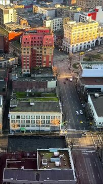 Aerial view looking down on Gastown streets in downtown Vancouver, with heritage brick buildings, rooftops and quiet intersections in warm evening light.