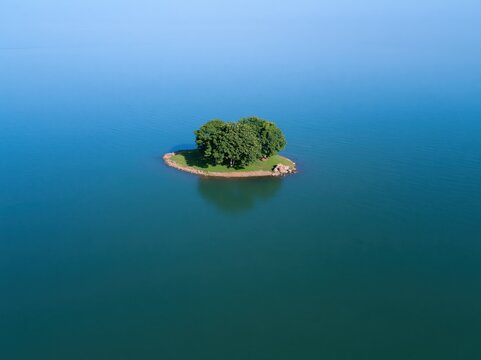 Small island with trees in the middle of a large blue lake
