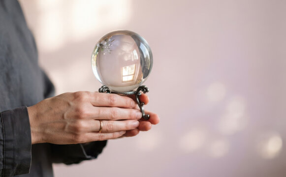 Woman holding a crystal ball on a stand representing future prediction, divination, and psychic power