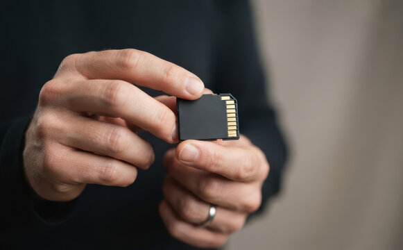 Person holding a blank SD memory card for data storage and digital photography concepts