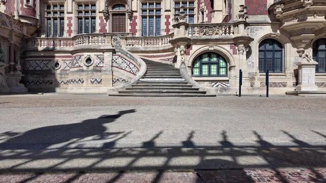 Palais B&eacute;n&eacute;dictine courtyard facade with a grand staircase, decorative balustrades, patterned masonry and arched windows in F&eacute;camp, Normandy, France