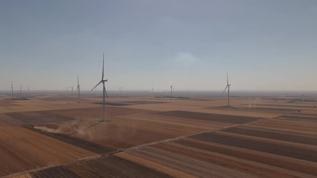 Wind Farm Above Plowed Fields with Dust Rising from Farm Tracks