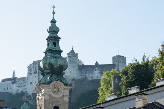 Historic church tower with castle walls and mountain backdrop