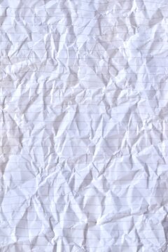 Close-up full-frame texture background of crumpled white lined notebook paper with creased folds and horizontal rules.