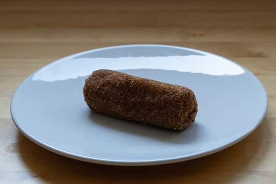 Breaded fish cake on a white plate