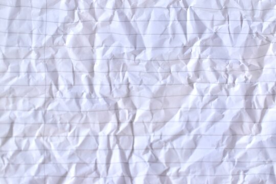 Close-up full-frame texture background of crumpled white lined notebook paper with creased folds and horizontal rules.