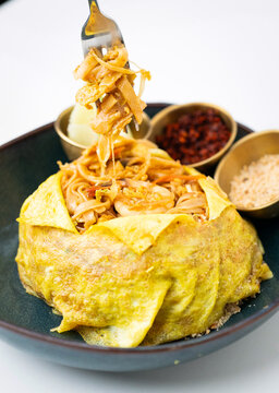 Stir-fried noodles, Traditional Thai pad, Thai wrapped in egg with big shrimps, Thai stir-fried noodles with shrimps and egg wrap, Thai food style, Thai street food, Pad Thai with Egg Wrap