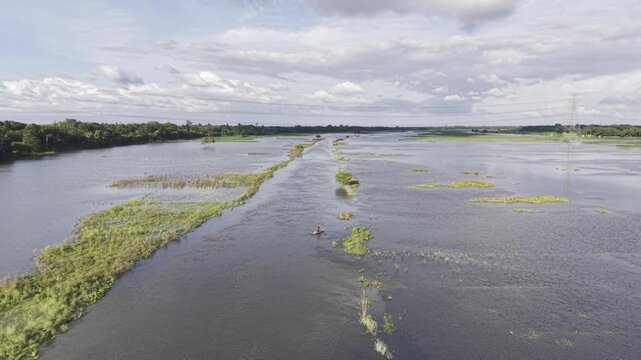 A person navigates a small wooden dinghy across waterlogged farmland at Nandiar Bil, Kushtia, Bangladesh, illustrating rural transport and seasonal flooding during the monsoon.