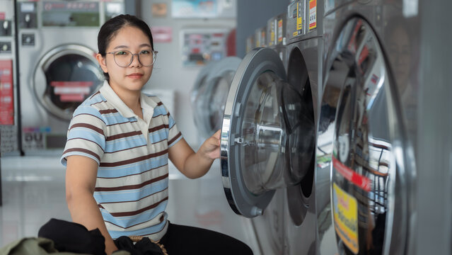 Asian people using qualified coin operated laundry machine in the public room to wash their cloths. Concept of a self service commercial laundry and drying machine in a public room