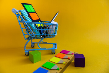 Shopping cart with school supplies, ruler and sticky notes on yellow background © Irina