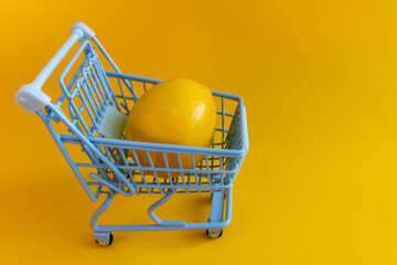Close angle of fresh lemon inside miniature cart on vivid yellow backdrop © Irina