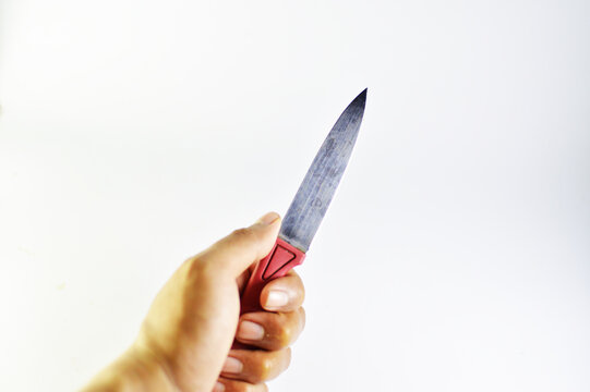Close up of a hand holding a sharp steel kitchen knife isolated on white background