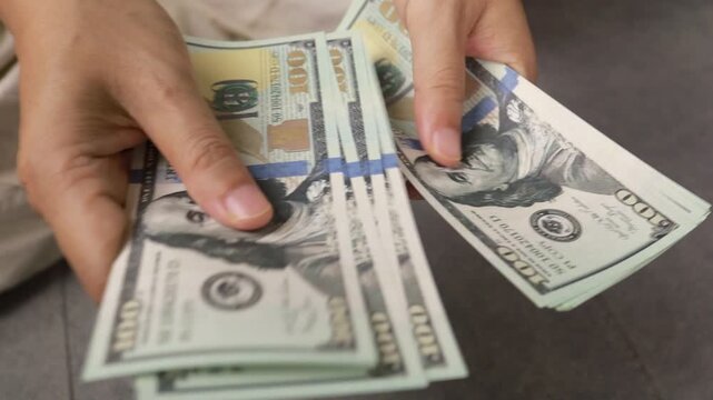 Person counting stack of hundred dollar bills