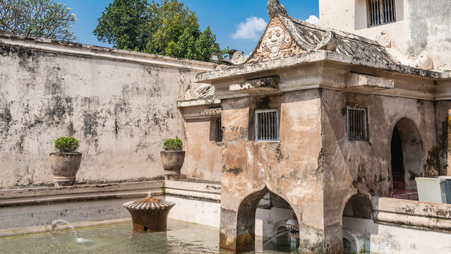 Ancient Hindu architecture. Famous Taman Sari Water Castle. Pool, bathing complex with fountains. Pavilion with ornaments, a bas‑relief of Kala Makara on the roof. Blue sky, clouds. Indonesia.Java
 

