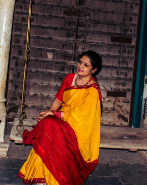 woman in saree sitting on old wooden swing, vertical