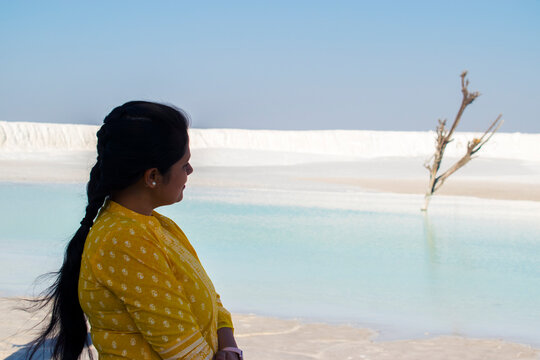 side portrait of woman in yellow dress at the background of blue water and white marble dumping Yard at Kishangarh in Rajasthan