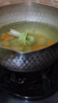 Boiling Traditional Herbal Drink Jamu Ingredients in Metal Pot on Gas Stove