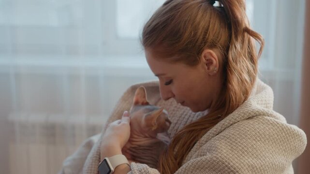 Close up of relaxed and contented woman holding affectionate pet. scene is softly lit with natural light emphasizing calm interaction between human and animal in what appears to be home