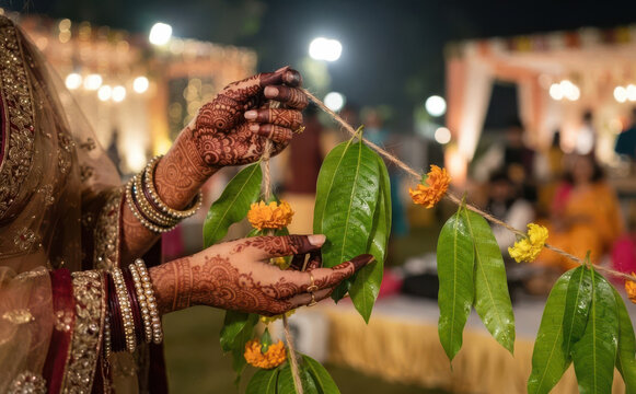 Indian bride preparing traditional mango leaf and marigold flower garland for wedding ceremony