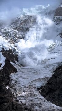 A massive snow avalanche falling down a steep mountain slope in the high alpine peaks