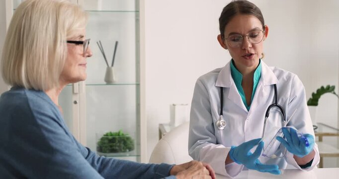 Doctor or nurse performing rapid laryngo diagnostic test on senior woman patient during clinic visit unpacking individual sterile throat swab and explaining procedure to detect bacterial infections