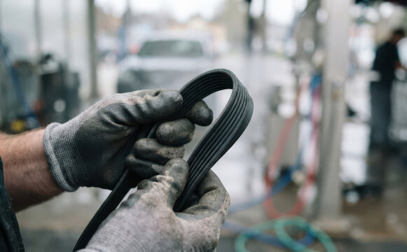 Mechanic holding a serpentine belt in an automotive repair shop for engine maintenance and vehicle service
