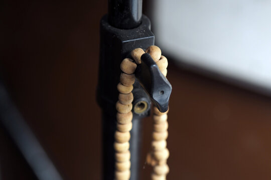 close-up of a string of wooden beads hanging over the tightening knob of a black metal tripod stand