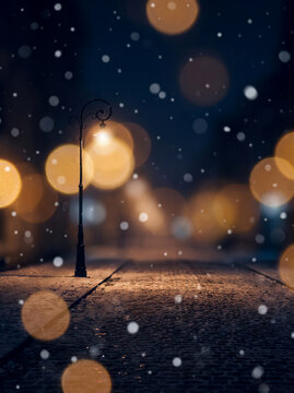 Vintage street lamp glowing on a snowy cobblestone street at night