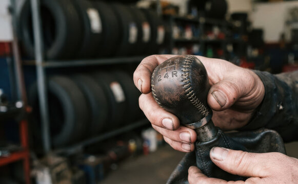 Mechanic holding manual car gear shift knob in automotive repair shop garage