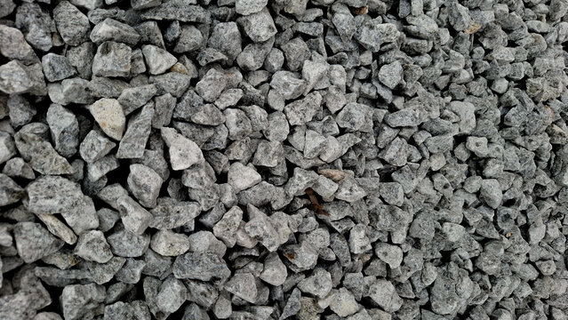 High angle close up view of angular grey crushed granite rock gravel. Abstract natural stone texture for building material and landscape design.