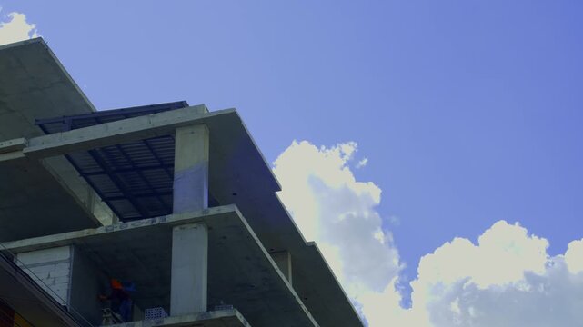 Pan right to left showing a worker on blue scaffolding