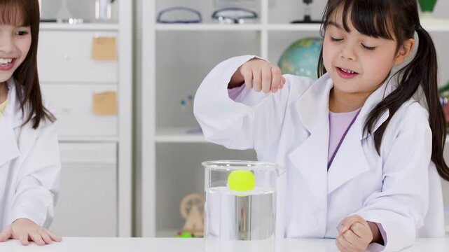 Two Elementary School Girls Conducting Sink or Float Science Experiment