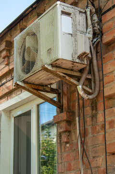 Exterior air conditioner unit mounted on a weathered brick wall near a window